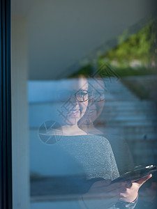 女人家用平板电脑,特写镜头透过窗户图片