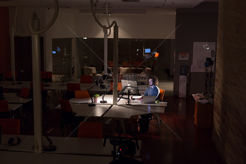 晚上黑暗的办公室里用电脑工作的轻人师稍后的时间工作