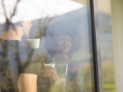 浪漫快乐的轻多民族夫妇他们豪华的家的窗边享受早晨的咖啡图片