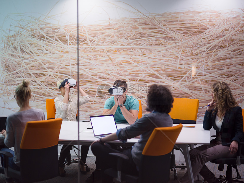 启动业务队夜间办公会议上用虚拟现实耳机,开发人员创意办公室的桌子周围与虚拟现实模拟器会图片