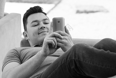 轻人躺沙发上用手机微笑图片