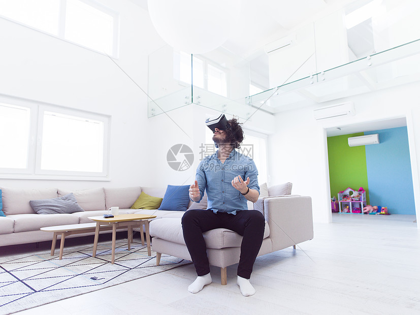 快乐的男人家里用虚拟现实的VR耳机眼镜获得经验图片