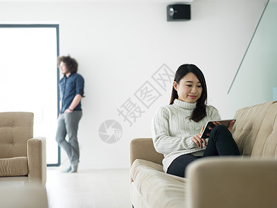 轻的多民族夫妇豪华的家放松,平板电脑客厅沙发上阅读图片
