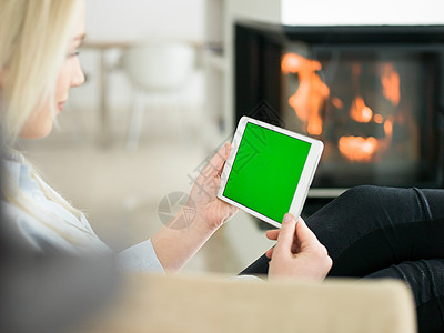 美丽的轻女人寒冷的冬天家里的壁炉前用平板电脑上网图片