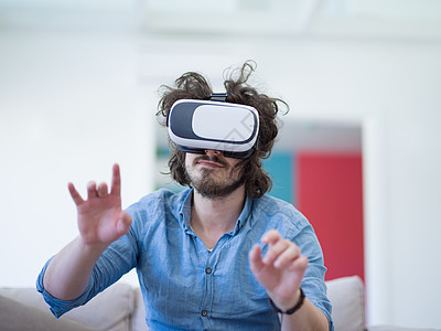 快乐的男人家里用虚拟现实的VR耳机眼镜获得经验图片
