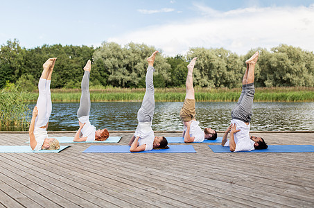 瑜伽,健身,运动健康的生活方式群人户外垫上支撑肩倒立姿势河湖泊图片
