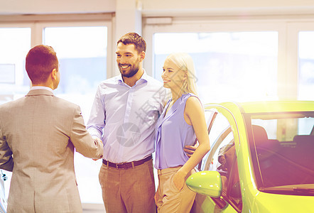 汽车业务,汽车销售人们的愉快的夫妇与经销商握手车展沙龙图片