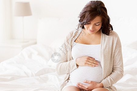怀孕,休息,人期望的快乐的孕妇坐床上,触摸她的肚子家里图片