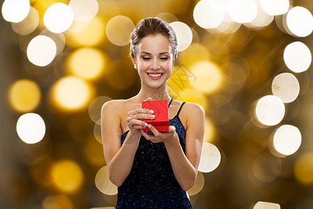 假日,礼物,奢侈人的微笑的女人穿着衣服,着红色的礼品盒灯光背景图片