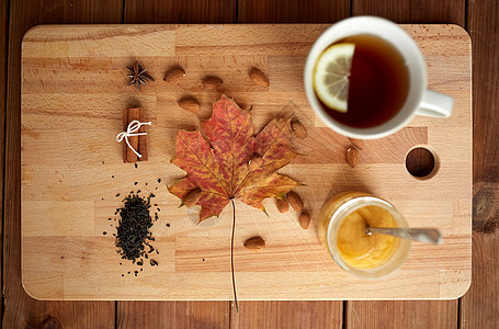 秋季民族科学柠檬茶蜂蜜木板上与枫叶杏仁木板上的柠檬茶蜂蜜图片
