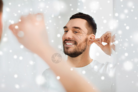 美丽,卫生人的微笑的轻人用棉签清洁耳朵,并家里的浴室里看镜子图片