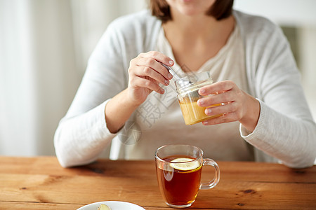 健康传统医学民族科学木桌上用柠檬蜂蜜喝茶的病妇图片