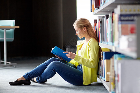 教育,高中,大学,学人的微笑的学生女孩读书,坐图书馆的地板上图片