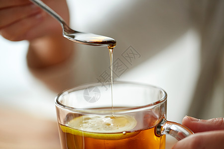 健康食品,饮食民族科学的密切妇女添加蜂蜜与柠檬茶杯图片