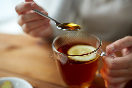 健康食品,饮食民族科学的密切妇女添加蜂蜜与柠檬茶杯图片