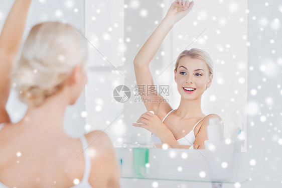 美丽,卫生,早晨人的微笑的轻妇女应用止汗剂贴除臭剂,并家里的浴室雪地上看镜子图片