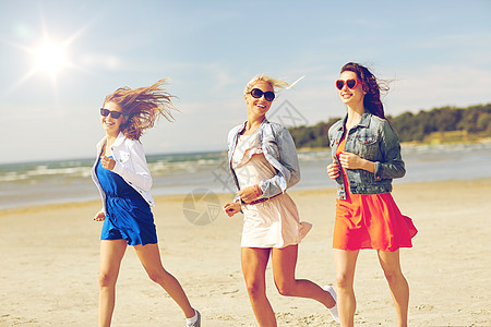 暑假,假期,旅行人们的群微笑的轻女,戴着太阳镜休闲服,沿着海滩跑步图片
