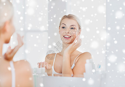 美丽,皮肤护理人的微笑的轻妇女应用奶油镜子家里的浴室雪图片