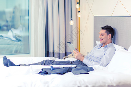 商业,技术,互联网酒店快乐的商人与平板电脑电脑躺酒店床上背景图片