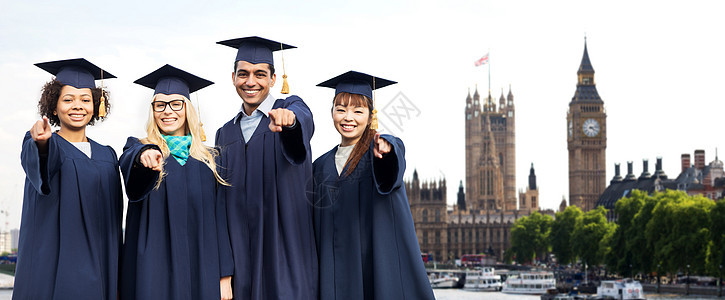 教育,毕业人的群快乐的国际学生迫击炮板学士学位礼服指向你伦敦城市的背景图片