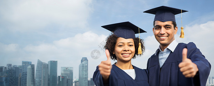 教育,毕业,手势人的快乐的国际学生砂浆板单身汉长袍户外竖大拇指新加坡城市摩天大楼的背景图片
