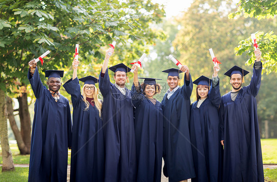 教育毕业人的群快乐的国际学生穿着灰浆板学士服,毕业证书庆祝成功图片
