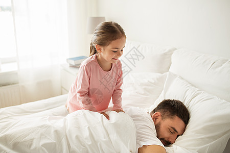 人们,家庭早晨的快乐的小女孩叫醒她熟睡的父亲家里睡觉图片