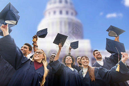 教育,毕业人的群快乐的国际学生穿着学士服,美国白宫背景下挥舞着迫击炮板帽子图片