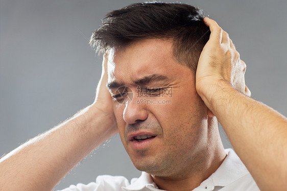 人,噪音压力的接近幸的人,遭受噪音覆盖他的耳朵,双手灰色的背景图片