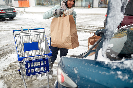 消费主义,交通人的妇女冬季停车时购物车汽车后备箱装载食物图片
