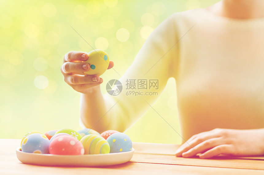 节日,传统人们的妇女的手与彩色复活节鸡蛋盘子上的绿灯背景图片