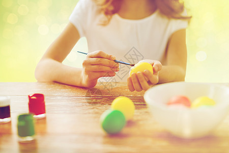 手工艺人的女孩着色复活节鸡蛋绿色假日灯光背景用刷子着色复活节彩蛋女孩图片