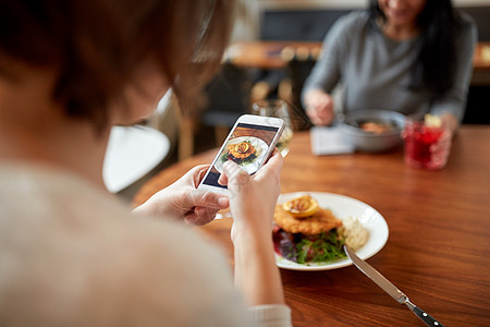 食物,新的北欧美食,技术人的妇女与智能手机包鱼片与酒石酱烤箱烤甜菜根番茄沙拉餐厅晚餐图片