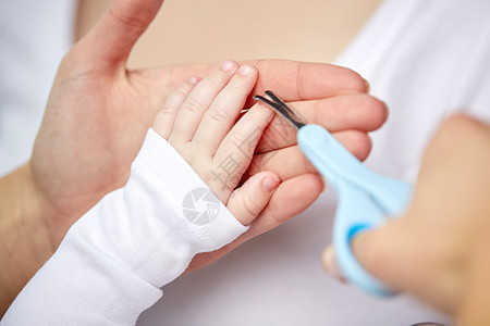 母亲人儿童保育的用剪刀修剪婴儿指甲把母亲的手收来背景图片