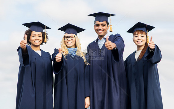教育毕业手势人的群快乐的国际学生穿着灰浆板学士服户外竖大拇指图片