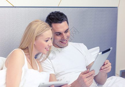 酒店,旅游,人际关系,技术,人际关系幸福的微笑的夫妇床上与平板电脑背景图片