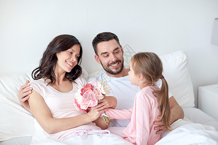 人,家庭,假期早上的快乐的小女孩家里的床上给妈妈送花图片