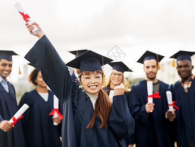 教育手势人的群快乐的国际学生穿着灰浆板学士服,毕业证书庆祝成功毕业图片