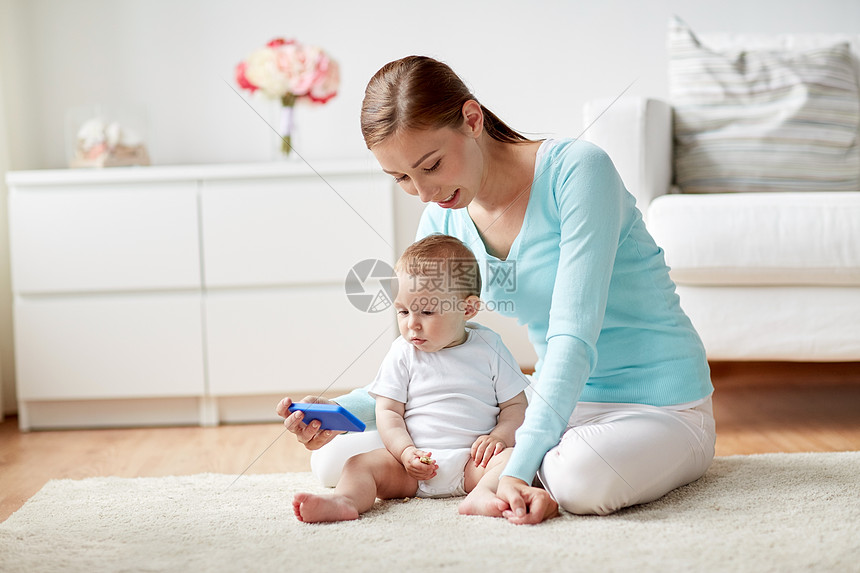‘~家庭,技术,孩子父母的快乐的微笑轻母亲向家里的小婴儿展示智能手机  ~’ 的图片