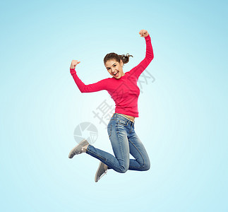 幸福,自由,权力,运动人的微笑的轻女人空中跳跃,举拳头蓝色的背景上微笑的轻女人空中跳跃图片