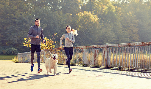健身,运动,人生活方式的快乐的夫妇与狗户外跑步快乐的狗户外跑步图片