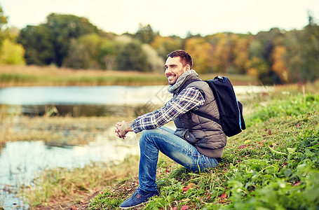 冒险,旅行,旅游,徒步旅行人们的微笑的人,背包休息河岸带着背包的微笑的人躺河岸上图片