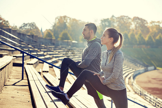 健身,运动,锻炼生活方式的夫妇伸展腿看台上夫妇体育场看台上伸展腿图片