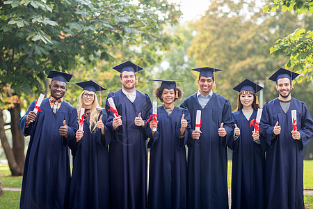 教育毕业手势人的群快乐的国际学生穿着灰浆板学士服,毕业证书竖大拇指文凭的快乐学生竖大拇指图片