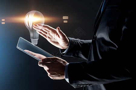 商业,人未来的技术商人的手与透明平板电脑电脑灯泡投影黑色背景用透明平板电脑商人图片