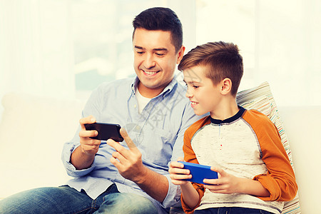 休闲,技术,家庭人的快乐的父子与智能手机短信家玩游戏快乐的父子家里智能手机图片