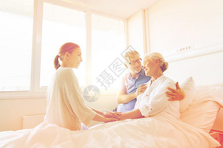 医学,支持,家庭保健人的快乐的老人轻的女人拜访欢呼她的祖母躺医院病房的床上幸福的家庭医院看望老妇女图片