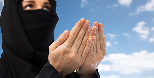 宗教,信仰,伊斯兰教人民的近距离祈祷穆斯林妇女头巾上的蓝天云背景近