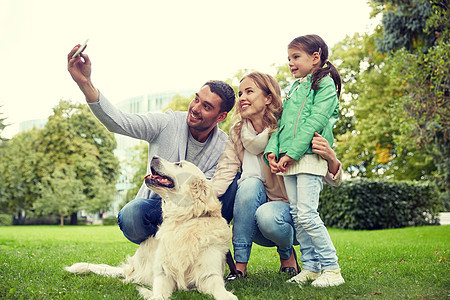 家庭,宠物,动物,技术人的快乐的家庭与拉布拉多猎犬公园用智能手机自拍快乐的家庭与狗自拍智能手机图片