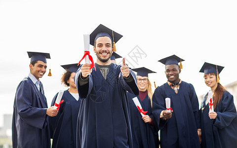 教育毕业手势人的群快乐的国际学生穿着灰浆板学士服,毕业证书竖大拇指文凭的快乐学生竖大拇指图片